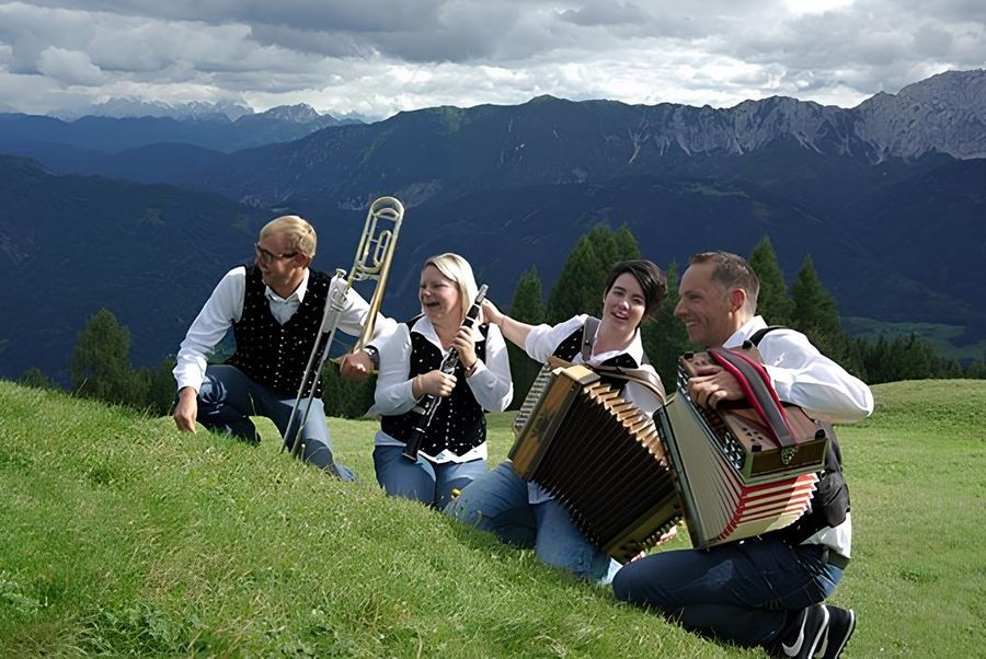 Eine Musikgruppe sitzt auf der Wieser bei der Alm und macht Musik